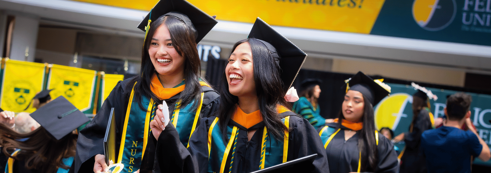 Two Female students smiling while walking back to their seats from getting their diploma