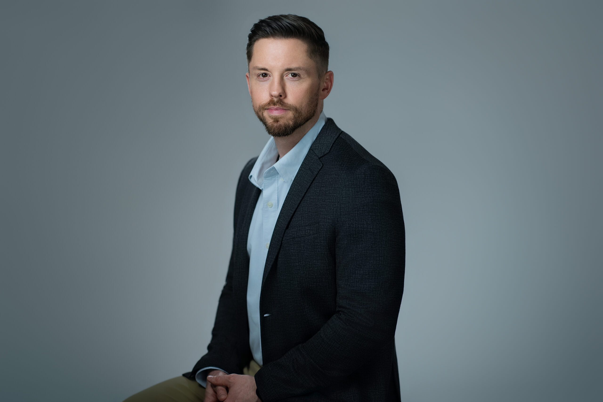 Felician professor Brad Ahern headshot shows man in a dark suit with light blue shirt.